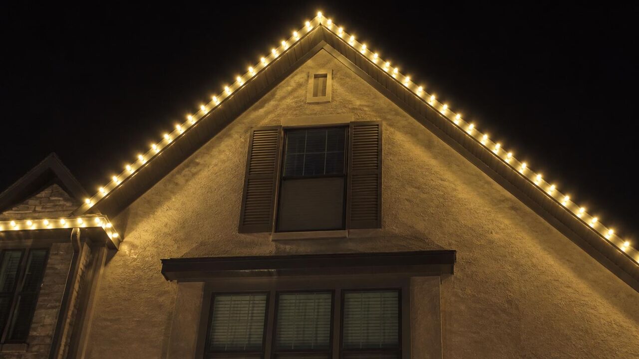Steep gable peak on a Lathrop home outlined in warm white permanent LED points against a night sky