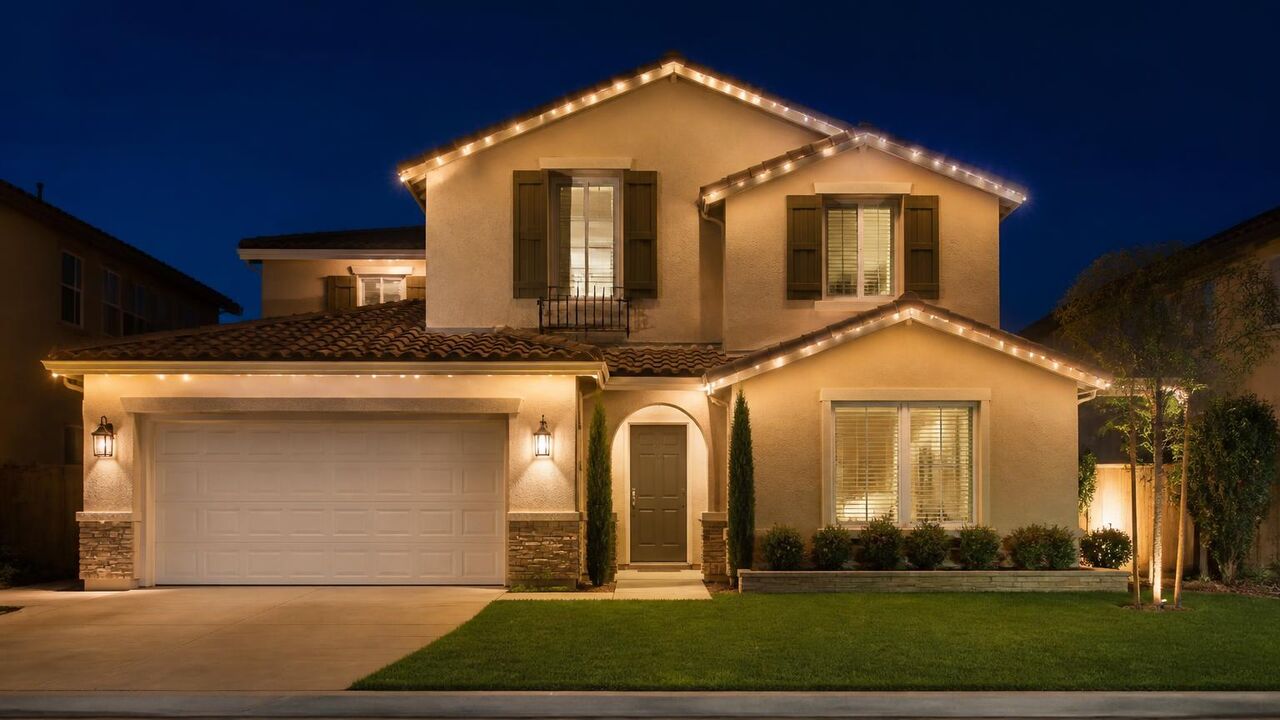 Two-story Lathrop stucco home with permanent Christmas lights outlining the second-story eaves and gable peaks