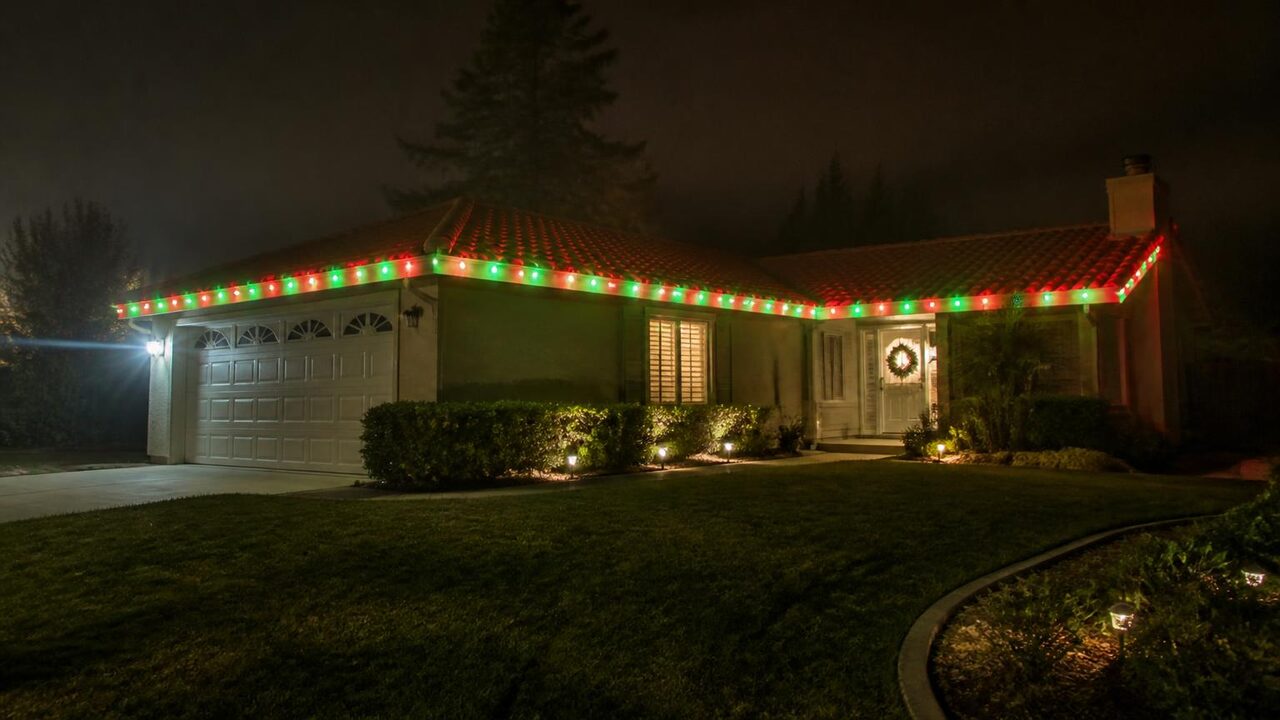 Permanent holiday lights set to alternating red and green Christmas colors on a Manteca home during winter tule fog