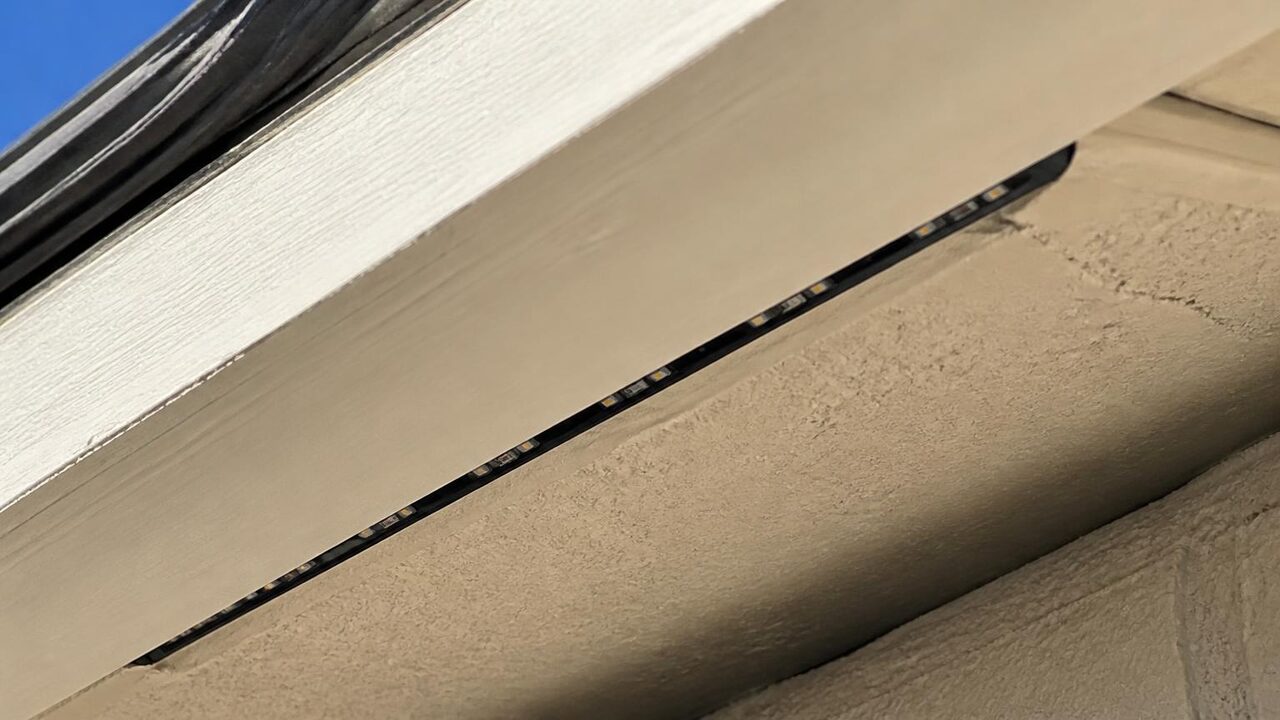 Close-up of permanent LED lights hidden inside a slim black channel tucked under the soffit of a Manteca house