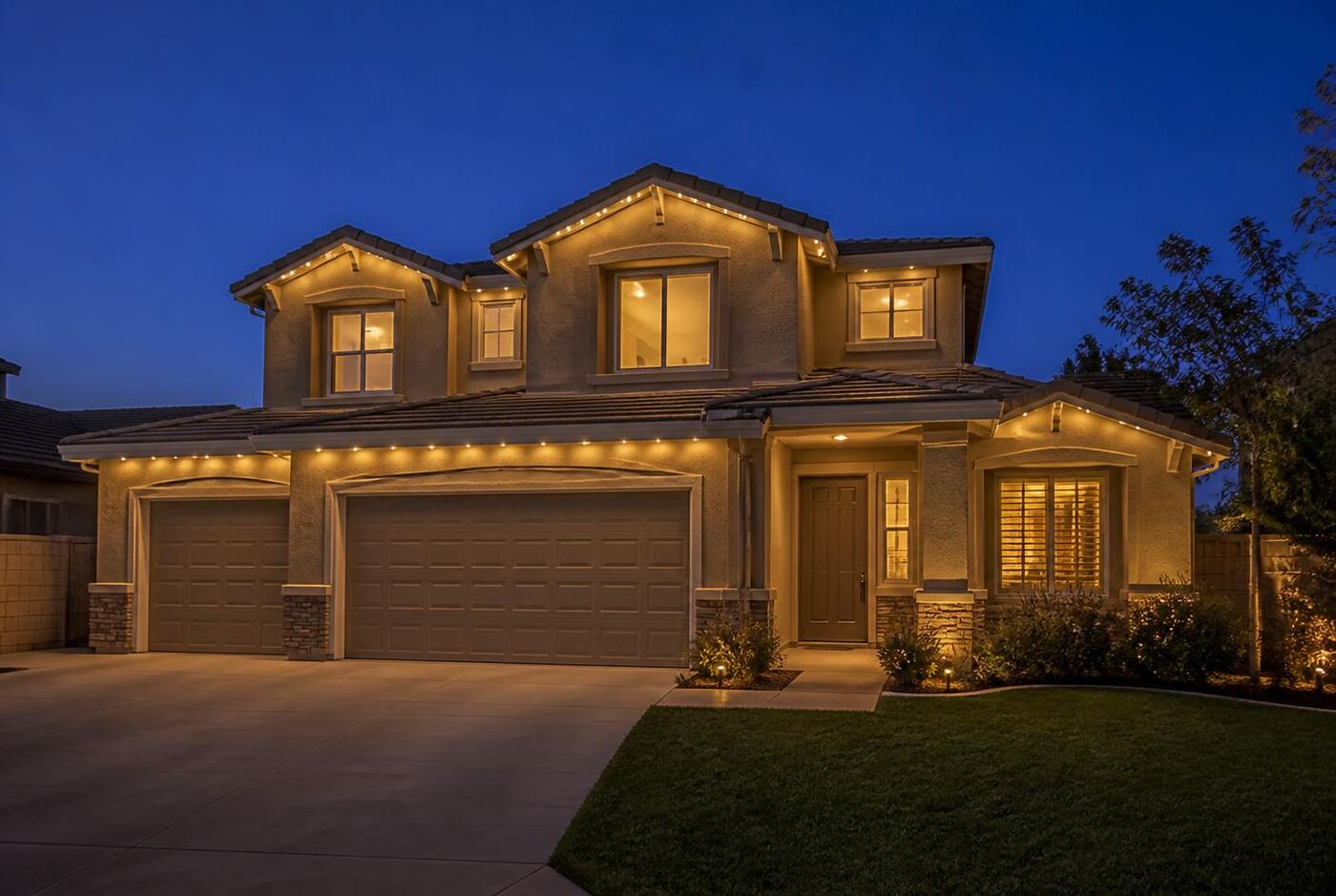 Two-story tract home with permanent lighting outlining the second-story roofline, gable peaks and garage eave