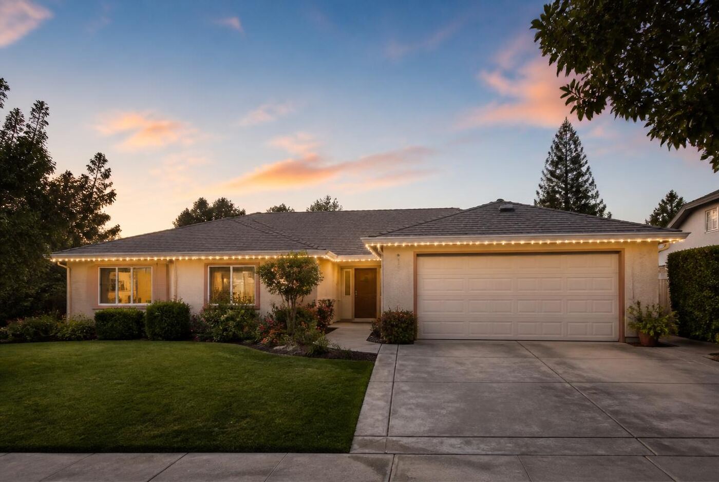 Single-story ranch style home with permanent lighting following the front roofline and garage eave