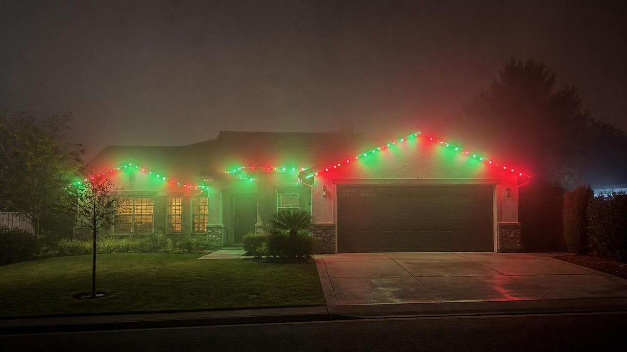 Tracy home running red and green permanent Christmas lights on a foggy December evening